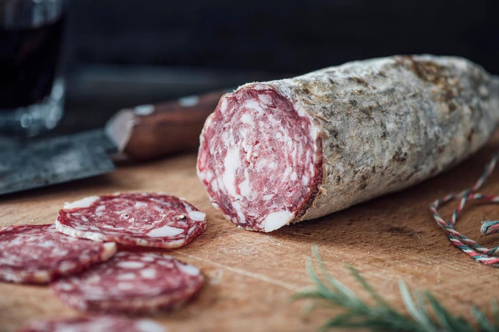 sliced dry-cured salami showing white Penicillium mold on natural casing